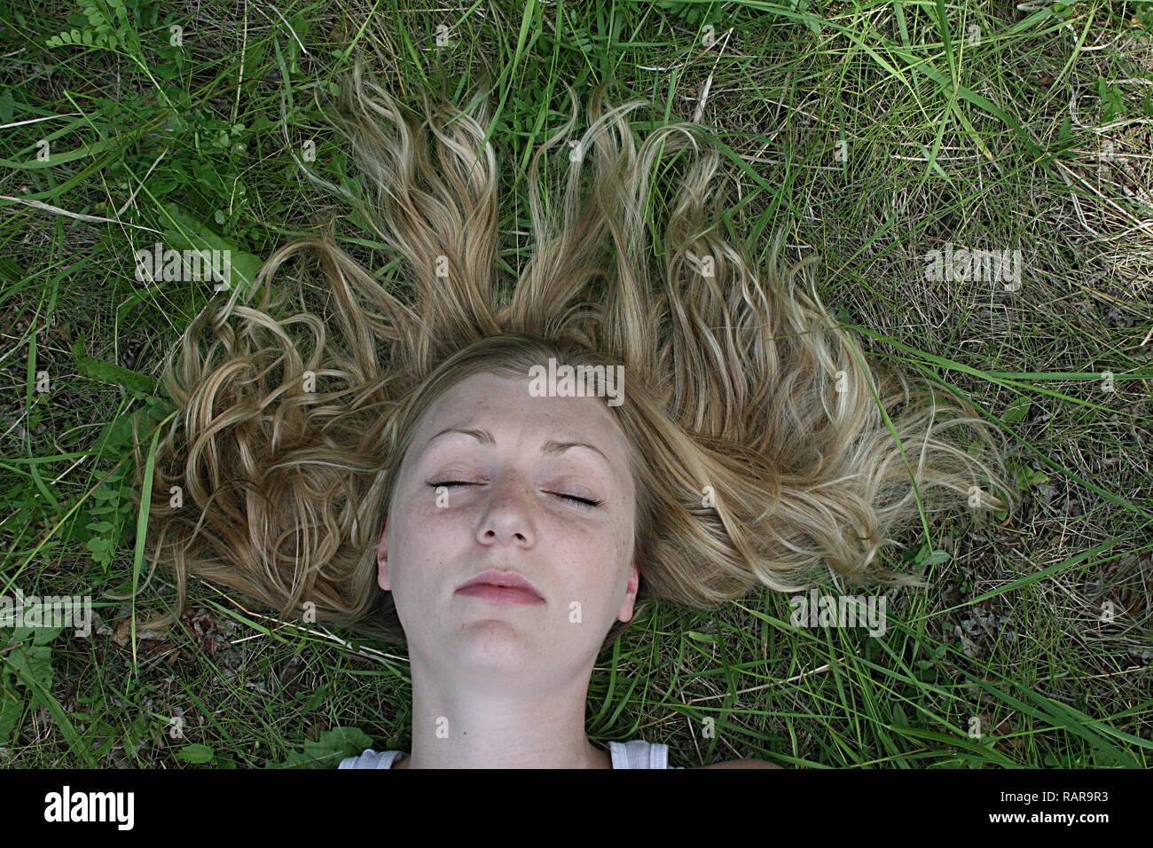 Frau liegt auf dem Rücken im Gras. Stockfoto