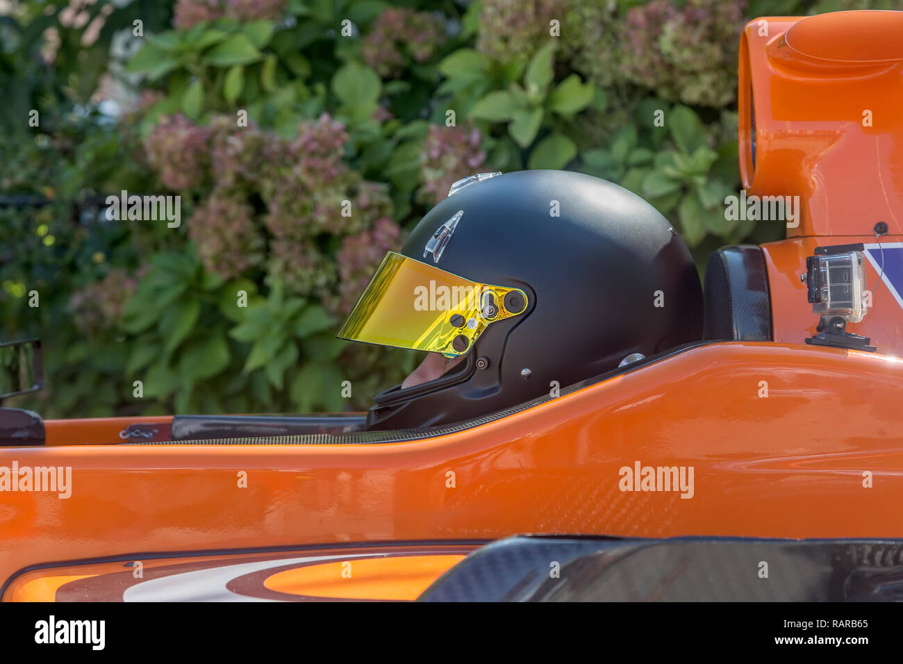 Fahrer im schwarzen Helm im Rennwagen sitzen Stockfoto