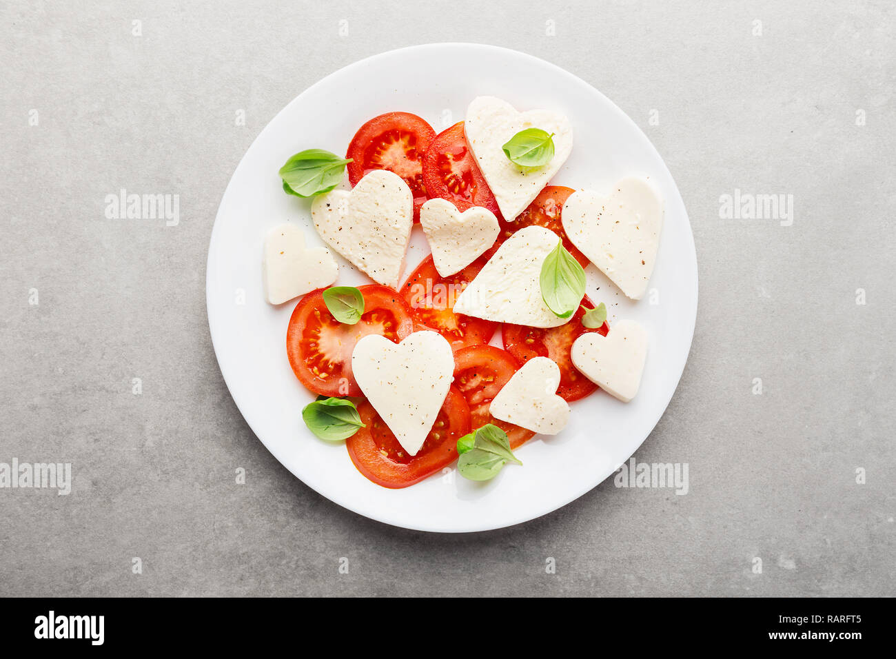 Valentines Tag Salat. Klassische italienische Caprese Salat mit Herz gebildet, Mozzarella, Basilikum und Tomaten auf dem Teller serviert. Oben betrachten. Kopieren Sie Platz. Stockfoto