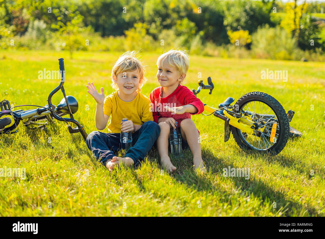 Zwei kleine Jungen Wasser trinken im Park nach dem Reiten ein Fahrrad Stockfoto