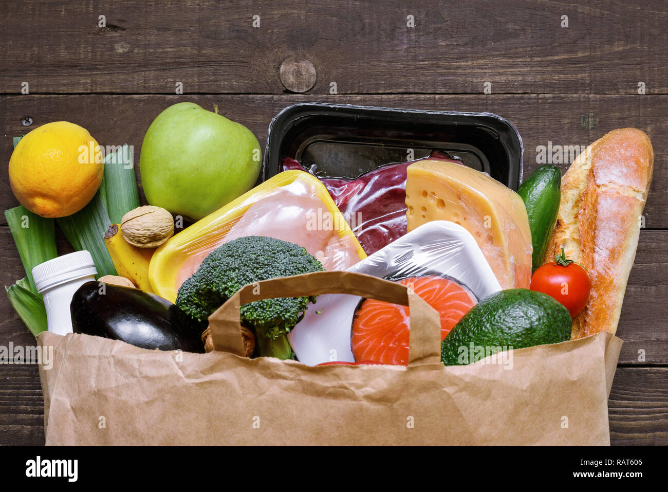 Full Paper bag verschiedener gesundes Essen auf weißem Holz- Hintergrund. Obst, Gemüse, Fisch und Fleisch. Ansicht von oben. Flach Stockfoto