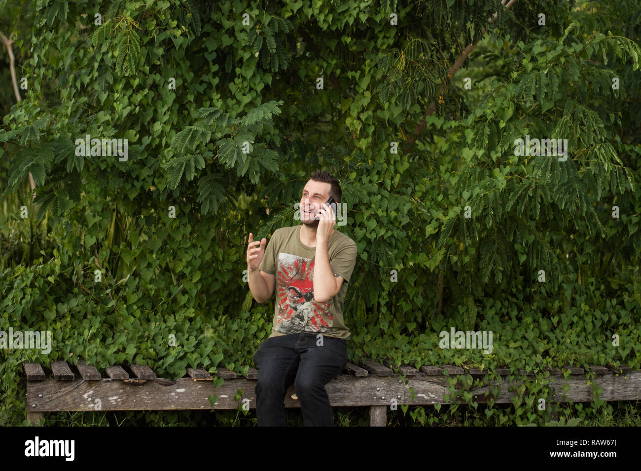 Mann mittleren Alters spricht in der Natur auf dem Handy. Stockfoto