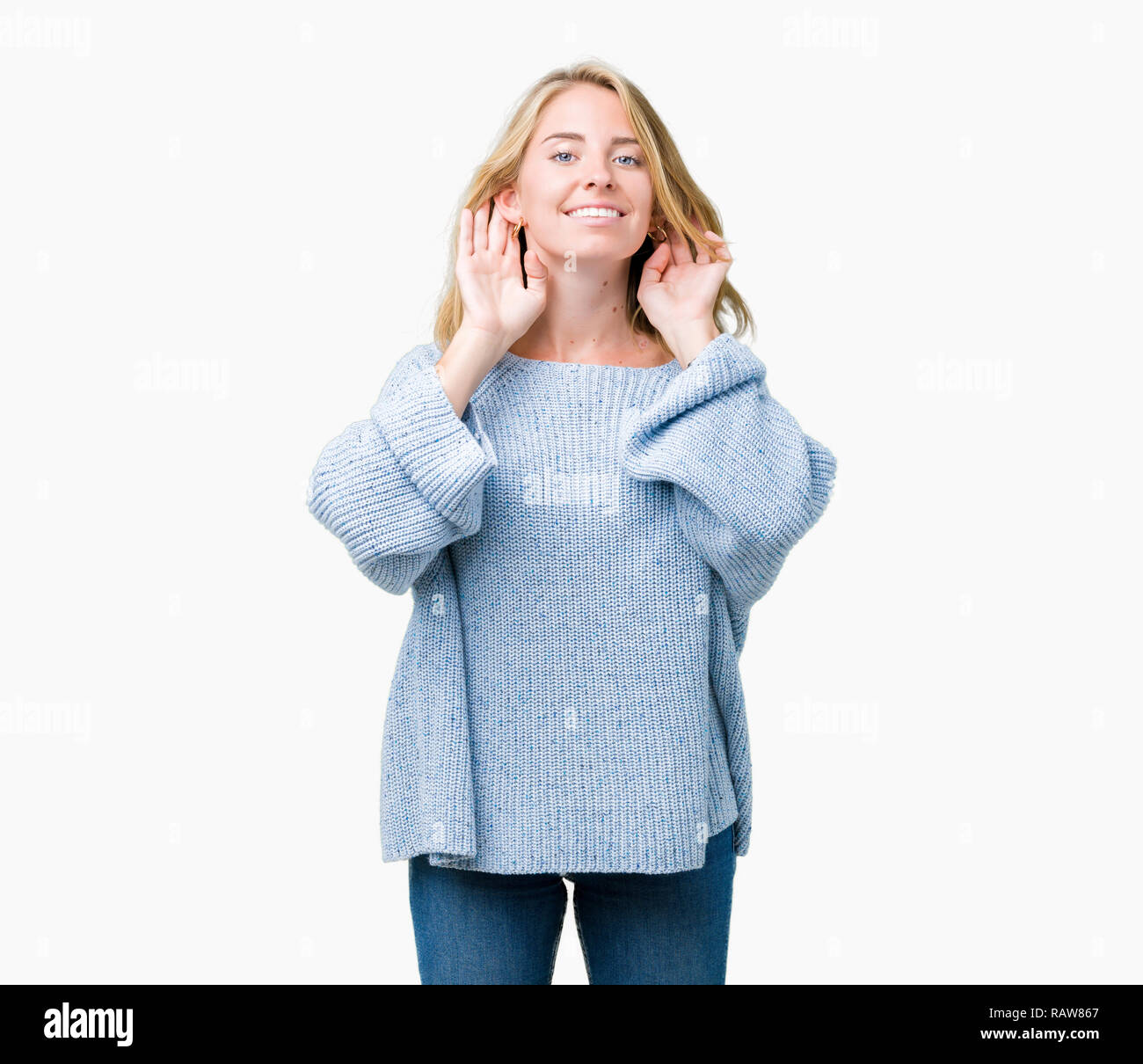 Schöne junge Frau trägt blaue Pullover über isolierte Hintergrund versuchen, beide Hände am Ohr Geste zu hören, neugierig, für Klatsch und Tratsch. Hörproblem, Dea Stockfoto