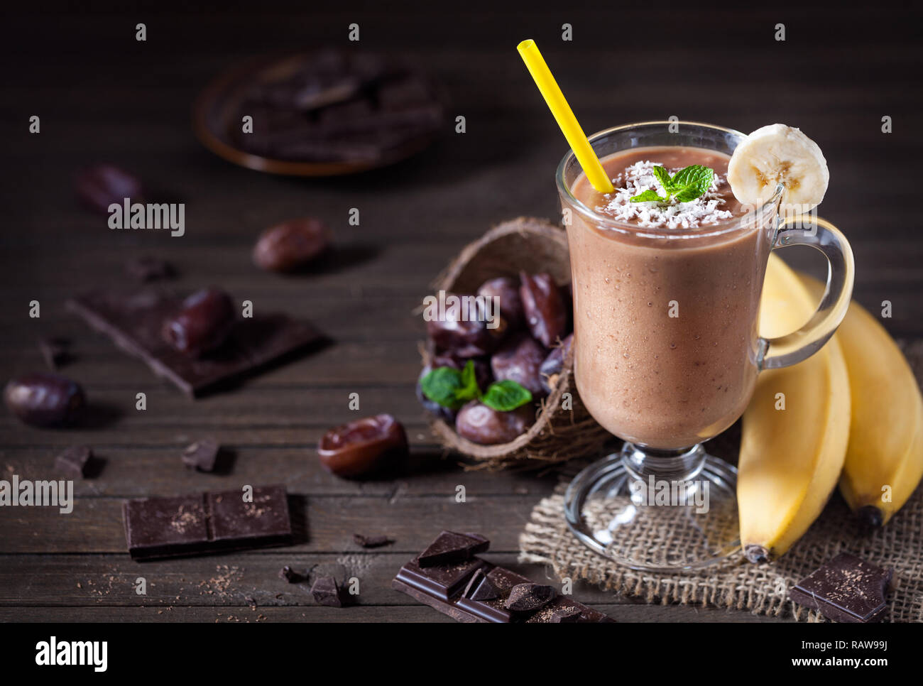 Süße Schokolade Banane Smoothie mit Kokosmilch und Termine mit Minze auf hölzernen Hintergrund Stockfoto