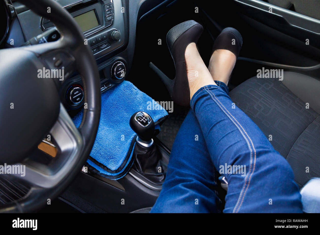 Die Füße der Frauen trägt blaue Jeans und in High Heels im Auto Stockfoto