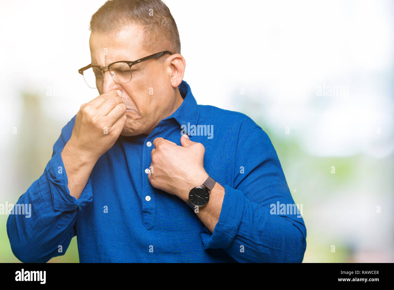 Mittleres Alter arabischer Mann Brille über isolierte Hintergrund riechen etwas stinkig und ekelhaft, unerträglichen Geruch, Atem wird mit den Fingern Stockfoto
