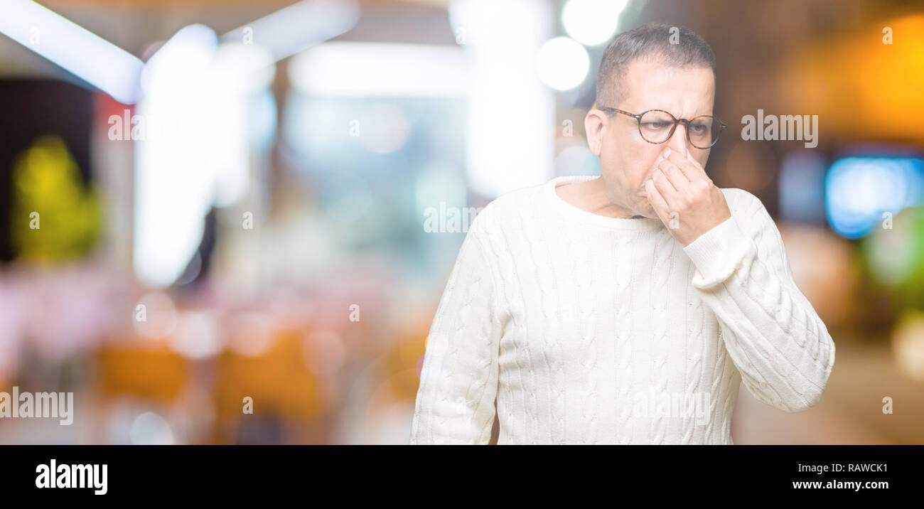 Mittleres Alter arabischer Mann Brille über isolierte Hintergrund riechen etwas stinkig und ekelhaft, unerträglichen Geruch, Atem wird mit den Fingern Stockfoto