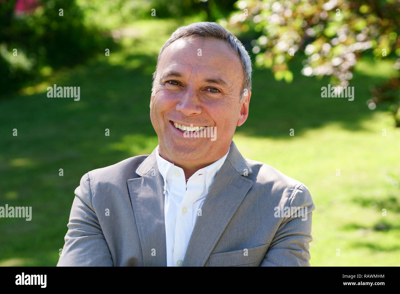 Eine Nahaufnahme, Porträt eines stolzen kaukasischen Mann trägt ein weißes Hemd, einen schwarzen Mantel und ein Lächeln in die Kamera. Stockfoto