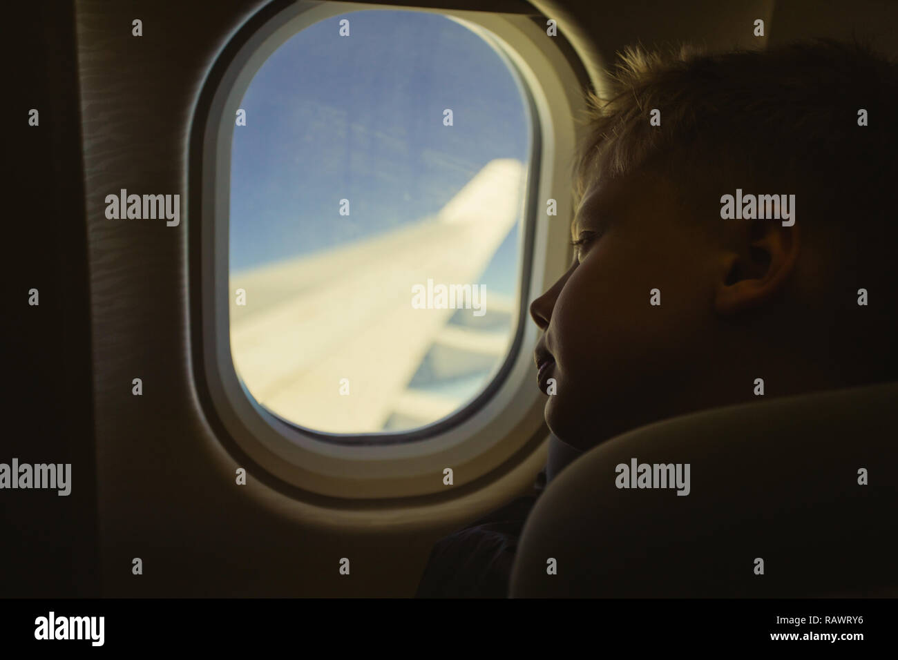 Cute white blonde Kind betrachten Fenster während der Sitzung in seinem Sitz während des Fluges. Farbe Fotografie gefiltert im Vintage Style. Stockfoto