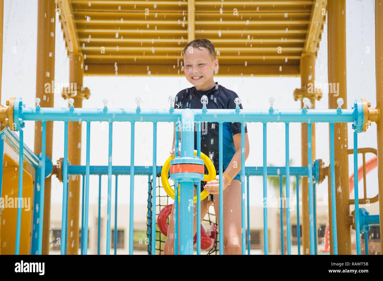 Glücklich lächelnde fröhlicher junger weißer Junge glücklich spielen auf Wasserrutsche im Aquapark. Sommer Urlaub am Strand. Vertikale Color Foto. Stockfoto