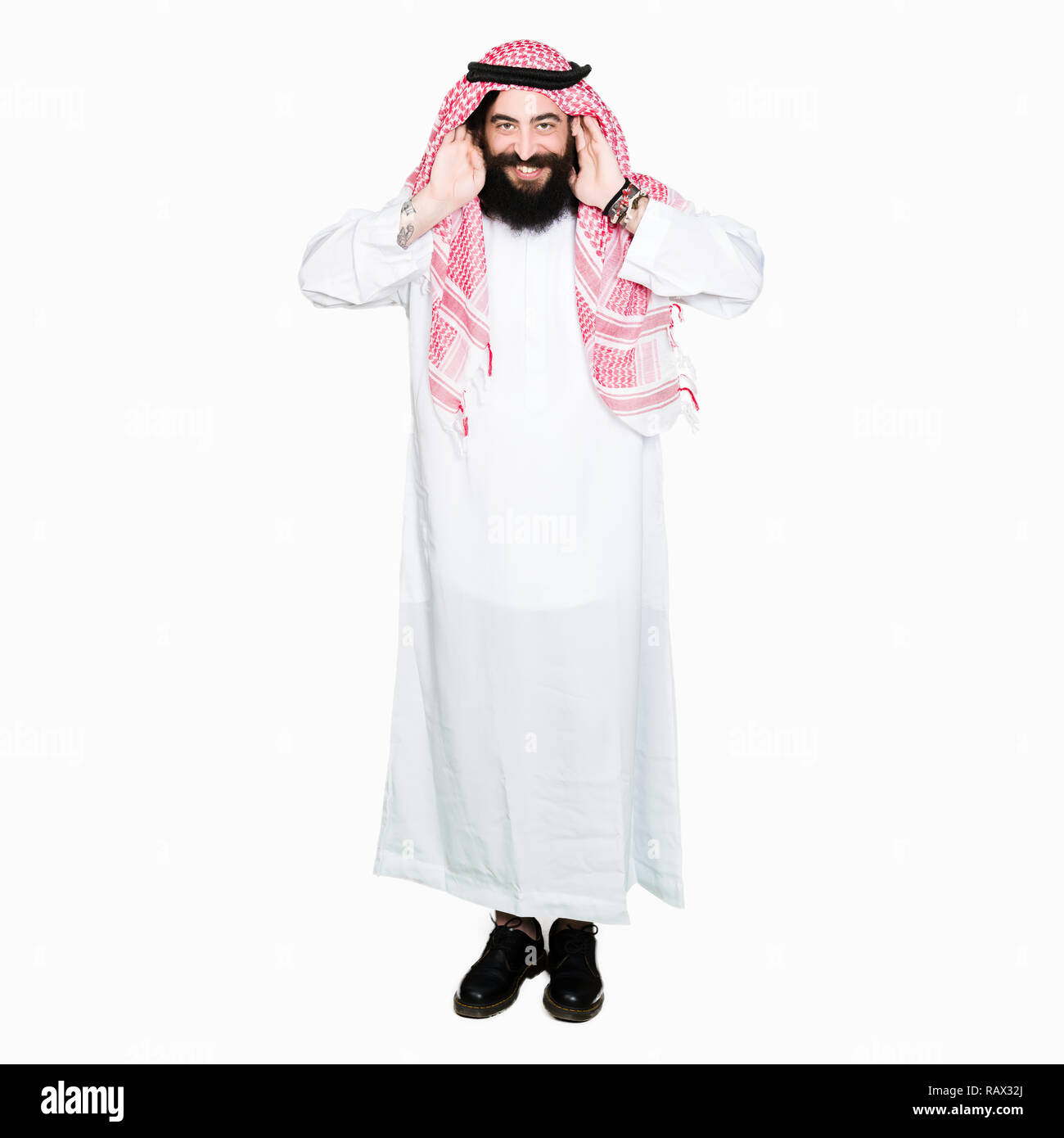 Arabian Business Mann mit langem Haar zu tragen traditionelle Kufiya schal Versuchen, beide Hände am Ohr Geste zu hören, neugierig, für Klatsch und Tratsch. Hörproblem, Stockfoto