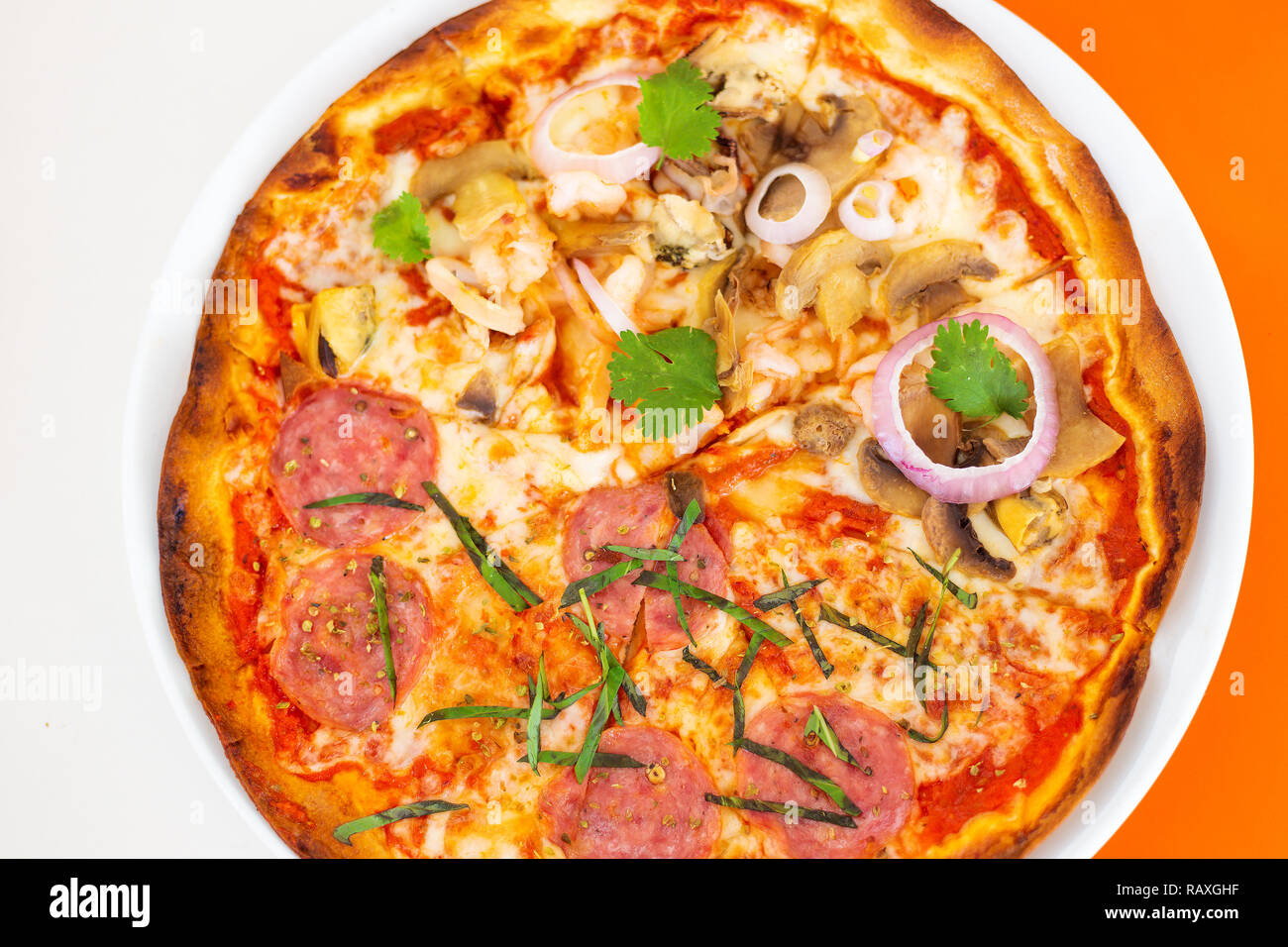 Halb Fisch, halb Pepperoni Pizza auf dünne Kruste, einschließlich Garnelen, Tintenfisch, Pepperoni, Schalentiere, Zwiebeln und Koriander oder Cilantro Stockfoto