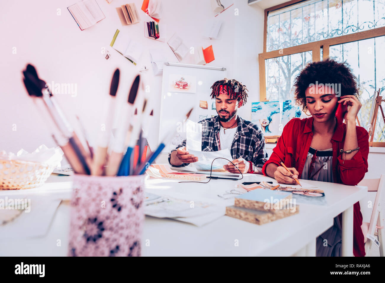 Innenarchitekten am Tisch sitzen mit Papieren und malen Bürsten Stockfoto