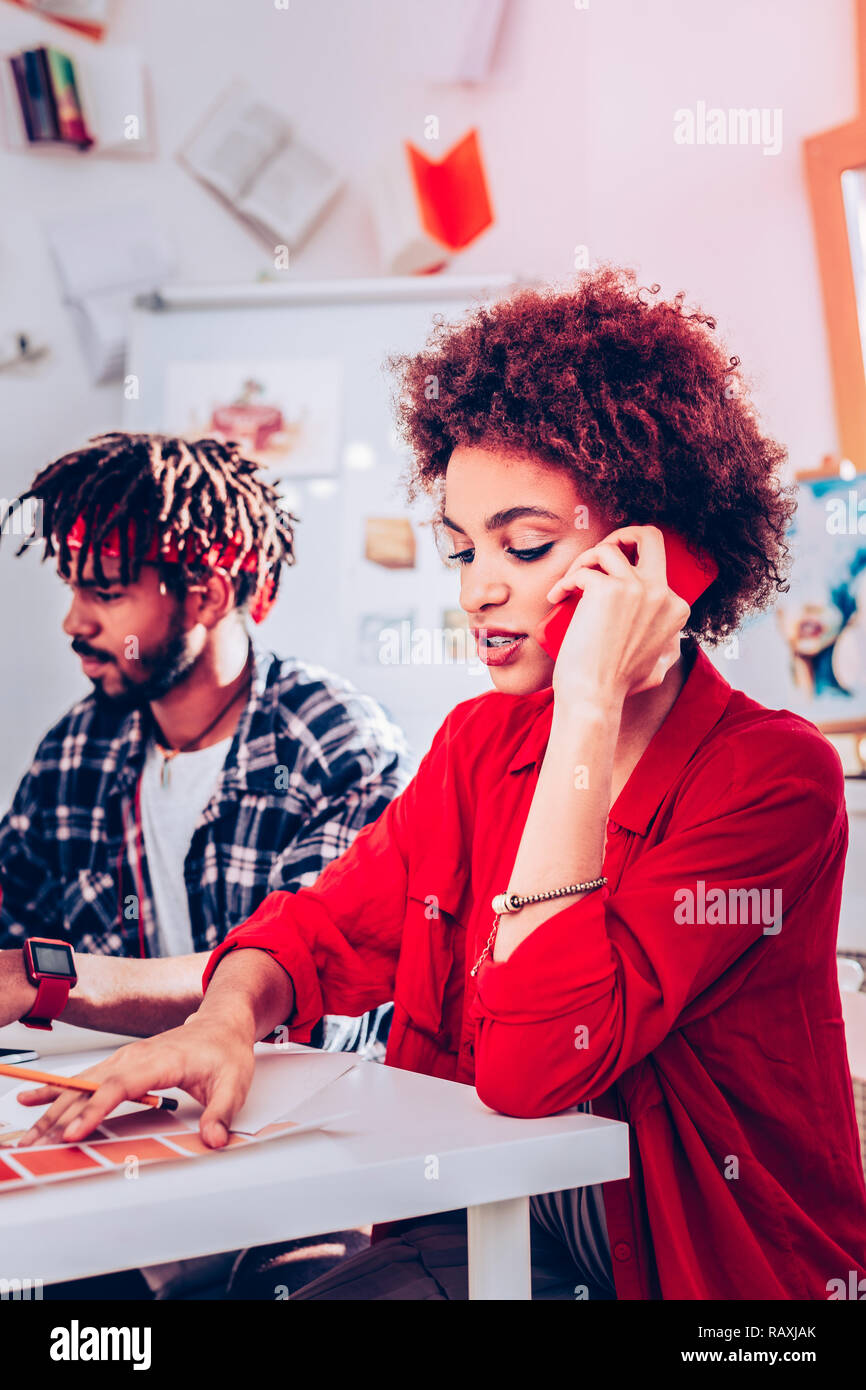 Curly Designer das Tragen der roten stilvolle Bluse Ihr Client aufrufen Stockfoto