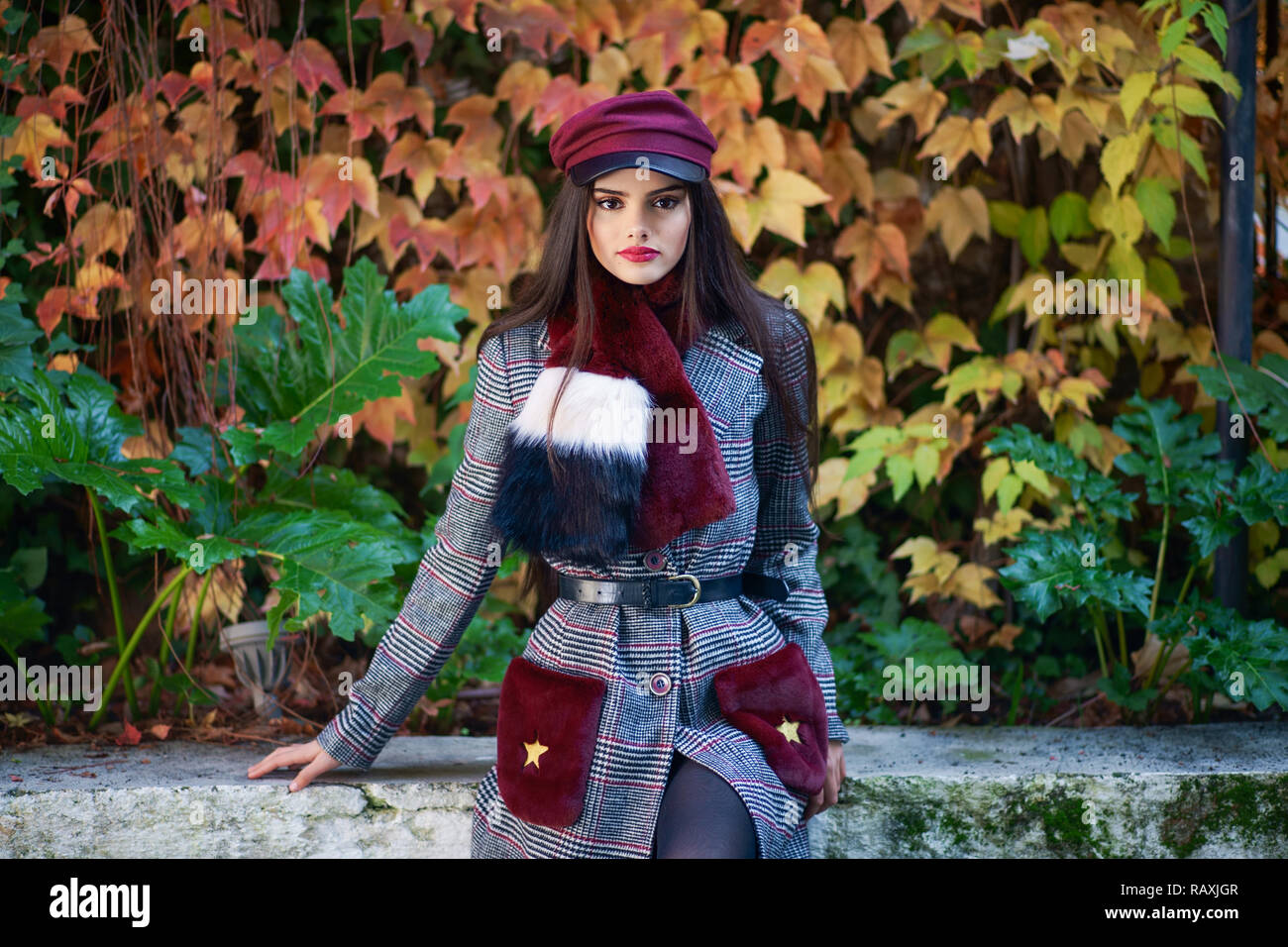 Junge schöne Mädchen mit sehr langem Haar zu tragen Winter Mantel und Kappe im Herbst Blätter Hintergrund. Lifestyle und Fashion Concept. Stockfoto