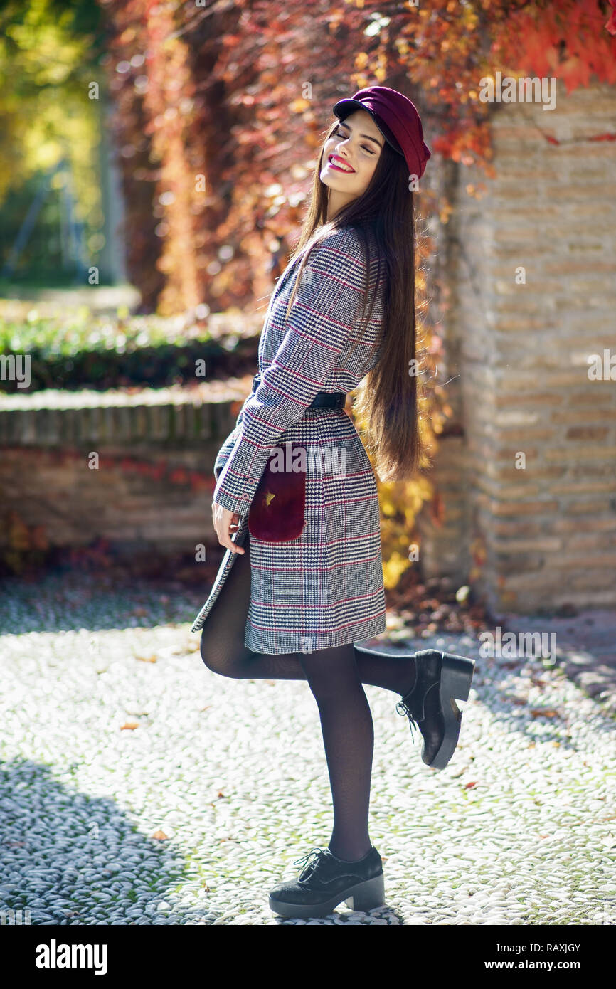 Spanien, Andalusien, Granada. Junge schöne Mädchen mit sehr langem Haar zu tragen Winter Mantel und Kappe im Herbst Blätter Hintergrund. Lifestyle und Mode con Stockfoto