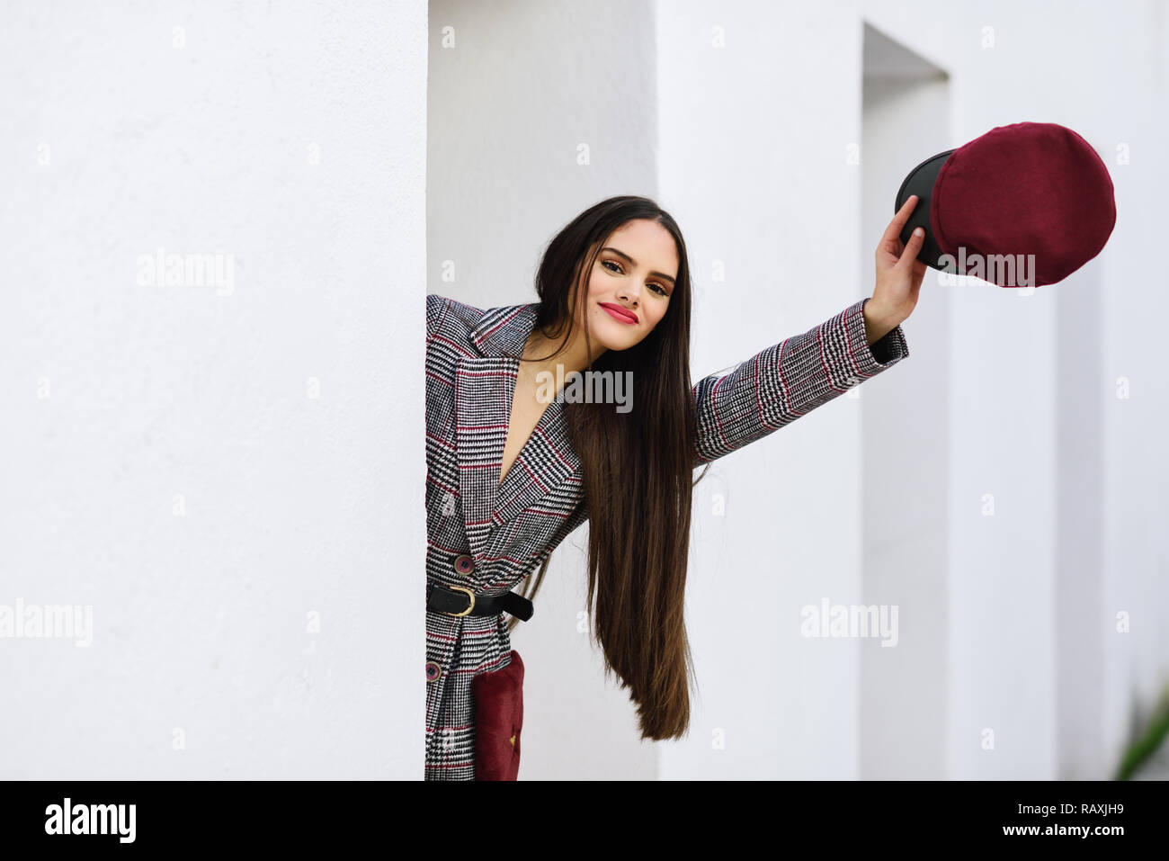 Spanien, Andalusien, Granada. Junge schöne Mädchen mit sehr langen Haaren auf Kamera tragen Winter Mantel und Kappe im Freien. Lifestyle und Mode Konz Stockfoto
