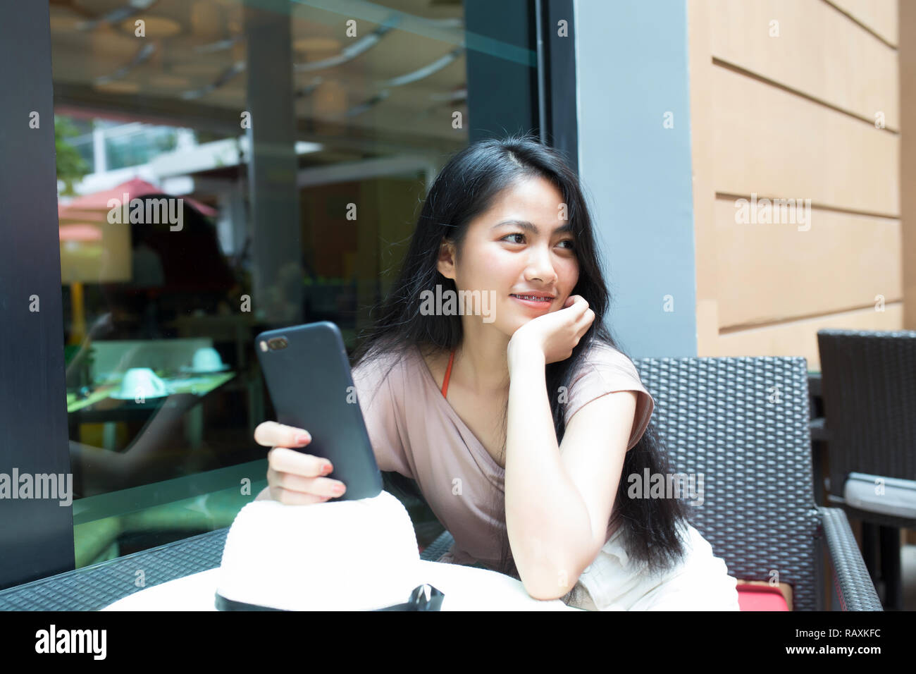 Hübsche asiatische Frau sitzt mit glücklich in der Coffee Shop und halten smart phone Stockfoto