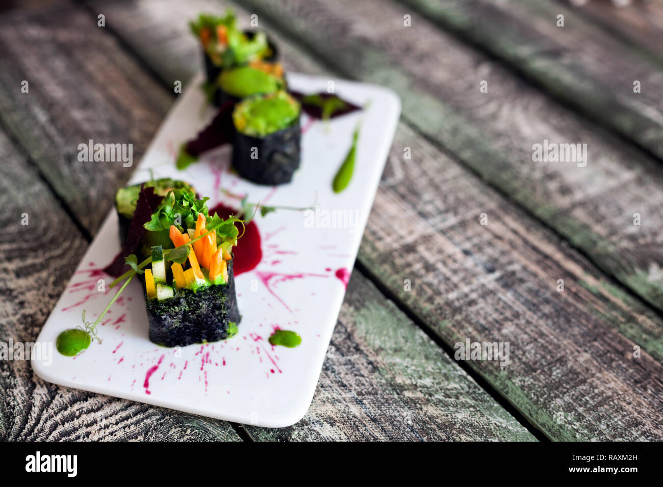 Raw vegan Sushi Rollen mit Gemüse und grüne Soße mit Food Styling im Restaurant Stockfoto
