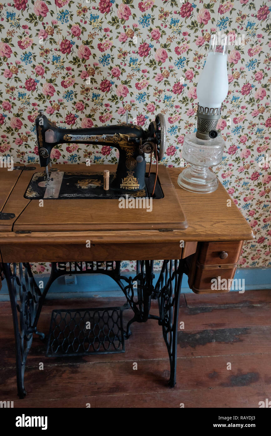 Vintage Sänger tritt Nähmaschine & antikes Glas salon Lampe auf bewaldeten Tabelle mit Vintage viktorianische Tapeten. Historisches Haus, McKinney, Texas. Stockfoto