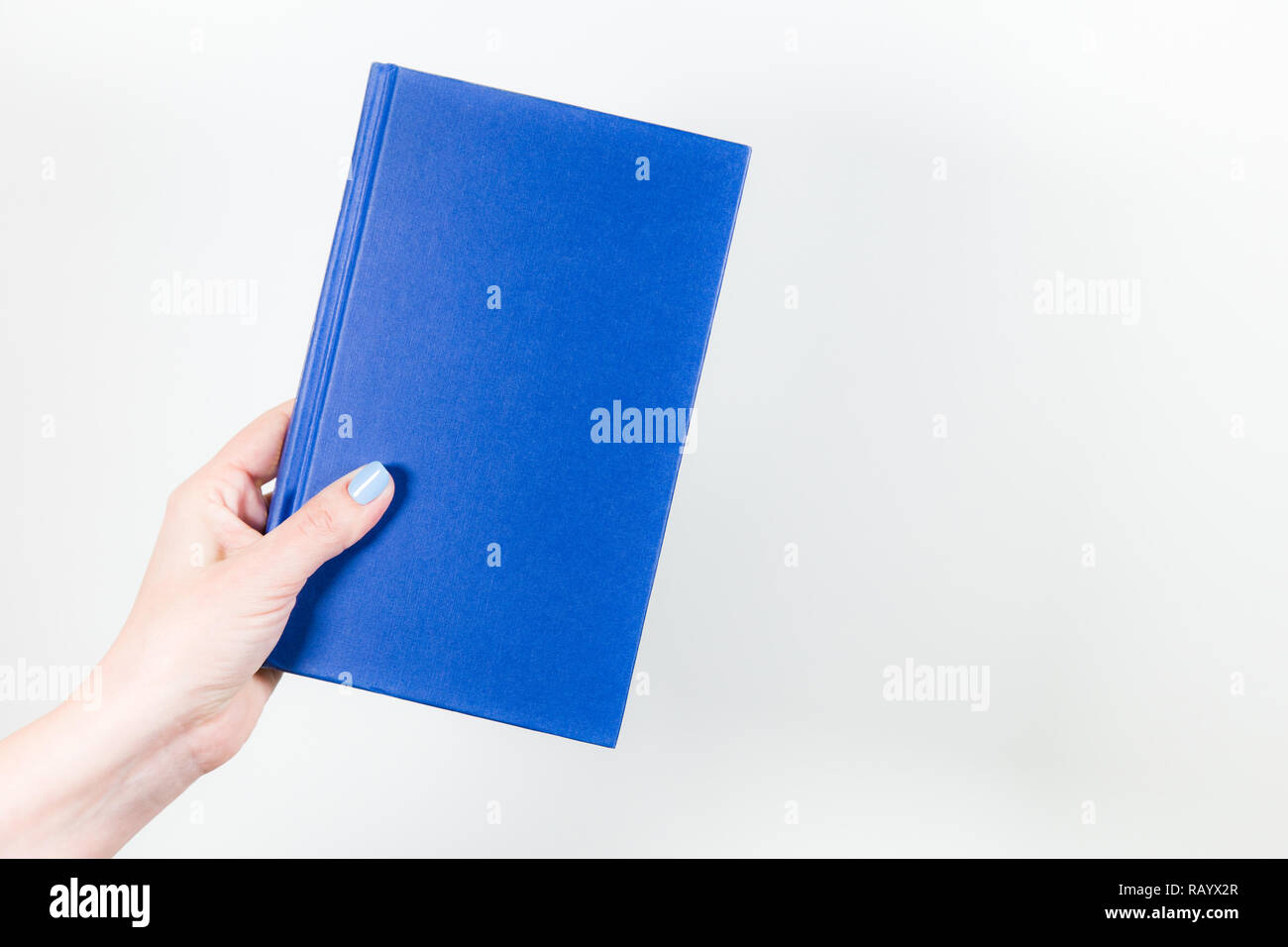 Detailansicht der weiblichen Hand mit blauem Papier Buch auf weißem Hintergrund. Horizontale Farbfotografie. Stockfoto