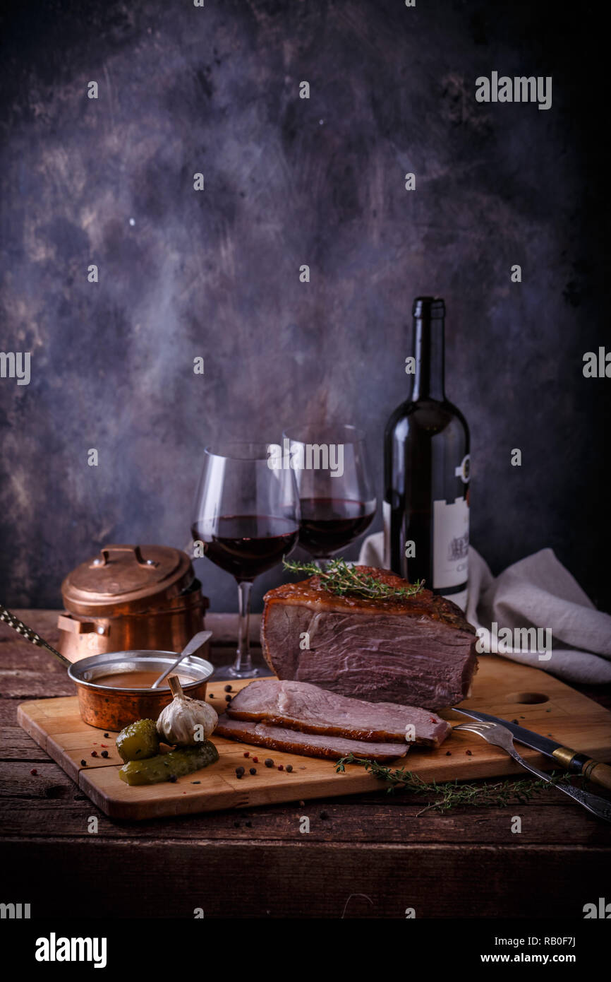 Gebackene Rindfleisch auf Holz Schneidebrett mit Soße, Essiggurken und Wein, kopieren. Stockfoto