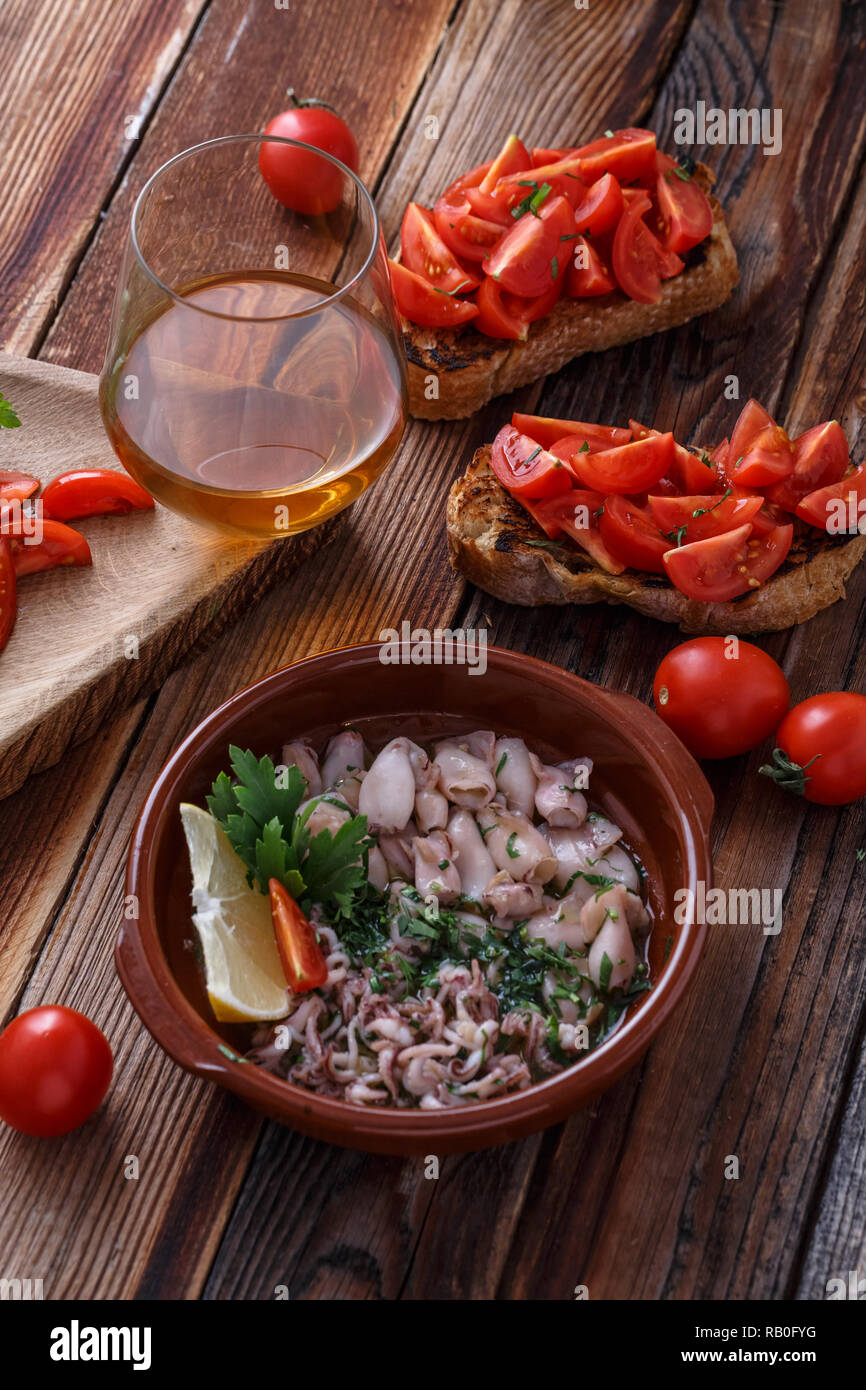 Baby Tintenfische in Olivenöl mit Bruschetta und Wein. Stockfoto