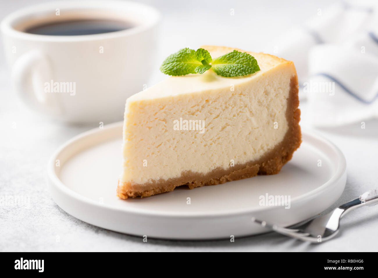 Lecker Plain New York Cheesecake auf weißen Teller dekoriert mit Mint Blatt. Detailansicht Stockfoto