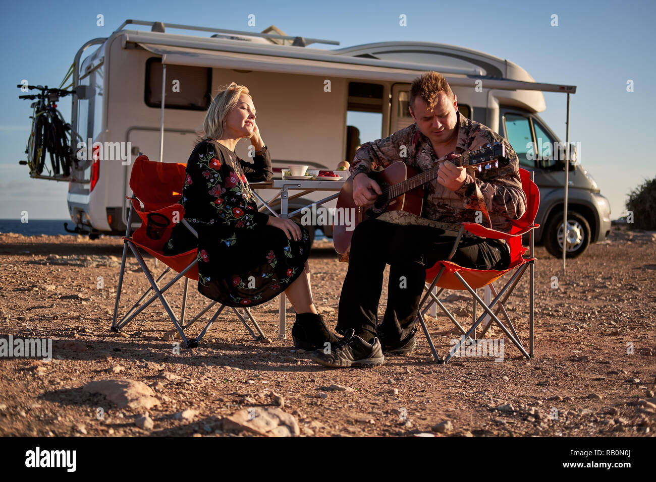 Im mittleren Alter reisende Paare sitzen auf Klappstühlen Pause während der langen Reise von den entspannenden Fahrzeug Motor home Trailer Stockfoto