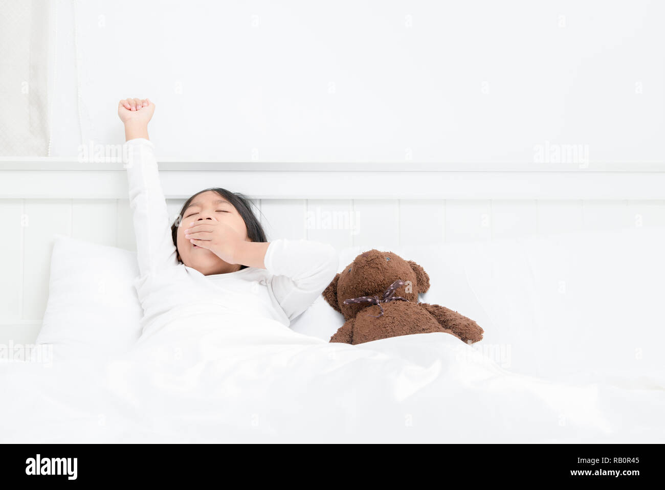 Kleines Mädchen, Gähnen und auf dem Bett am Morgen dehnen. faul Konzept Stockfoto