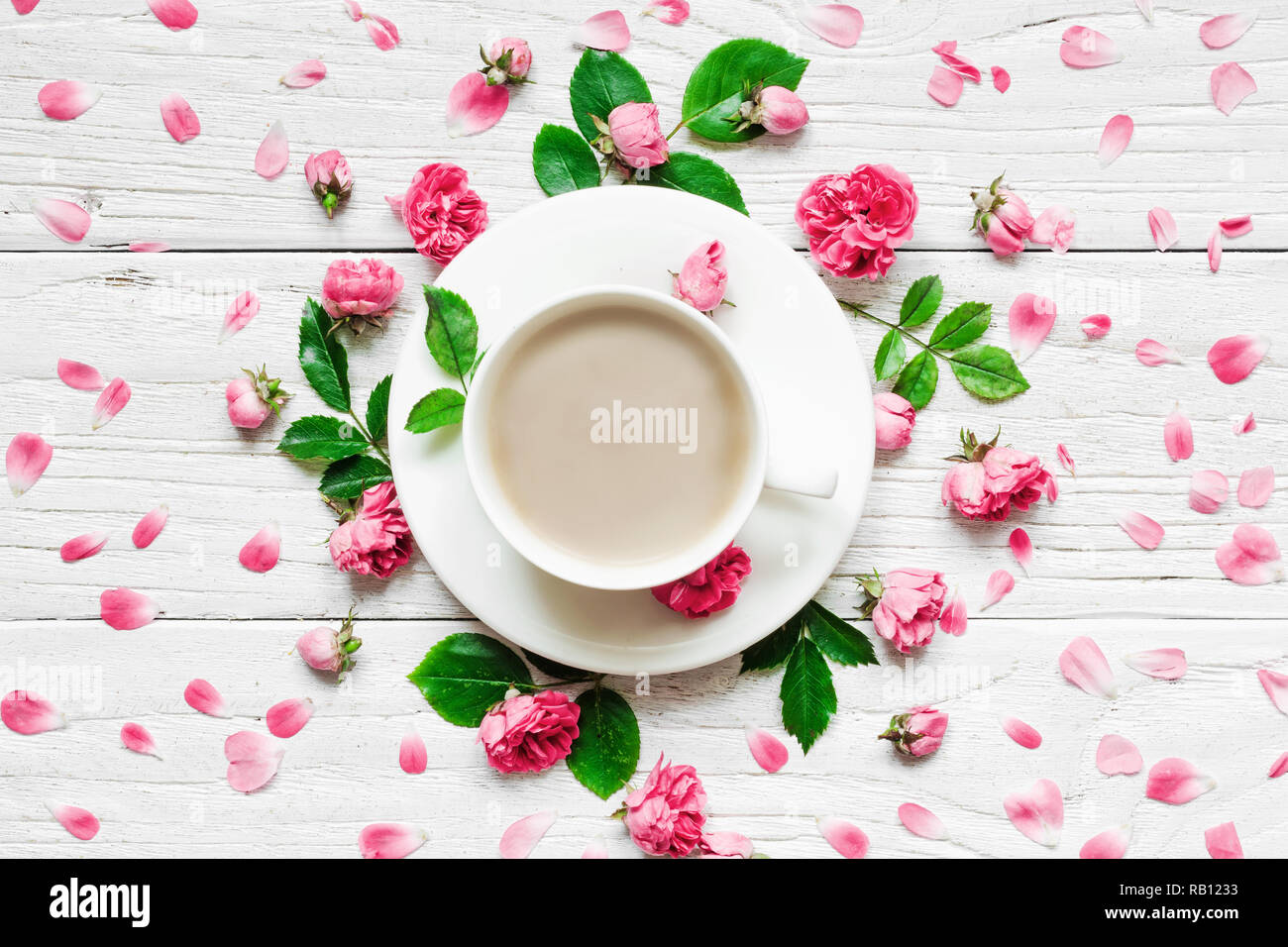 Blumen Komposition. Rahmen aus frischen rosa Blüten mit Tasse Cappuccino auf weißem Holz- Hintergrund. Flach. Mock up. top View Stockfoto