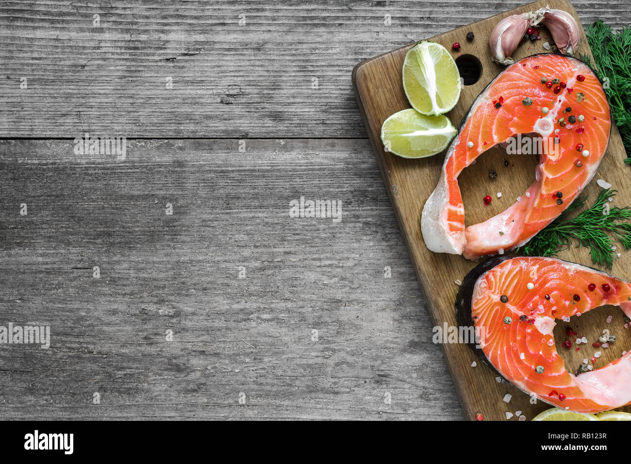 Roher Lachs Steak mit Kräuter, Zitrone und Pfefferkörner auf Holz Schneidebrett. gesunde Ernährung Lebensmittel. Ansicht von oben mit der Kopie Raum Stockfoto