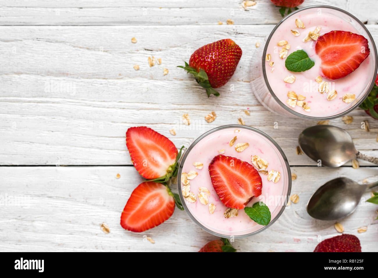 Gesunde Erdbeer Joghurt mit Haferflocken und Minze in Gläsern mit frischen  Beeren und Löffel über weiße Holztisch. gesundes Frühstück. Ansicht von  oben mit der Kopie s Stockfotografie - Alamy