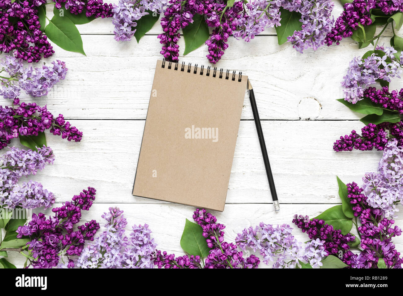 Kreative Gestaltung mit lila Blumen und leeren hipster Notebook auf weißem Holz- Hintergrund. Mock up. Hochzeit. Feder minimalen Begriff Stockfoto