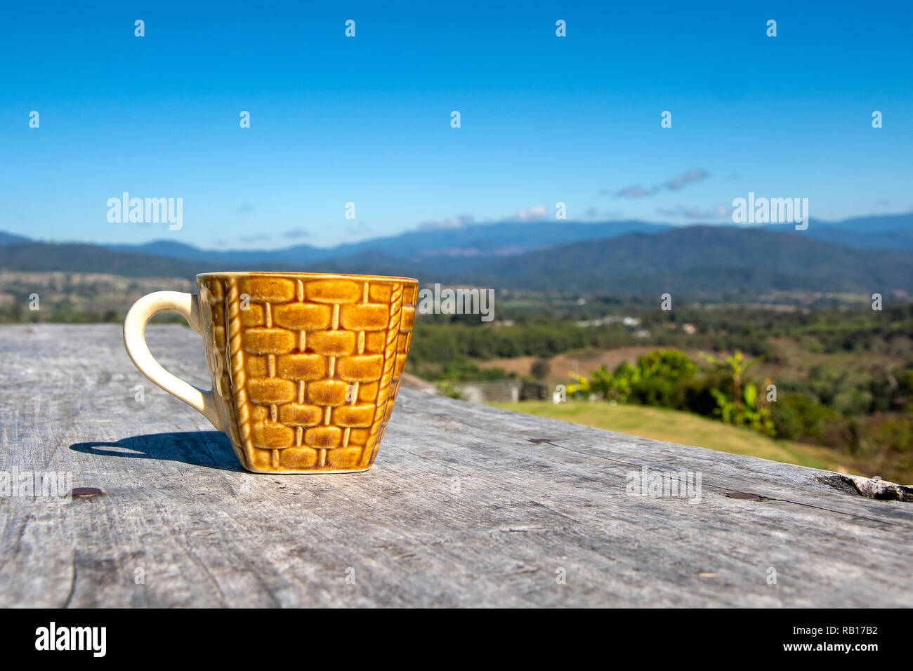 Kaffeetasse auf Holztisch mit blauem Himmel und herrlichem Bergblick. Stockfoto