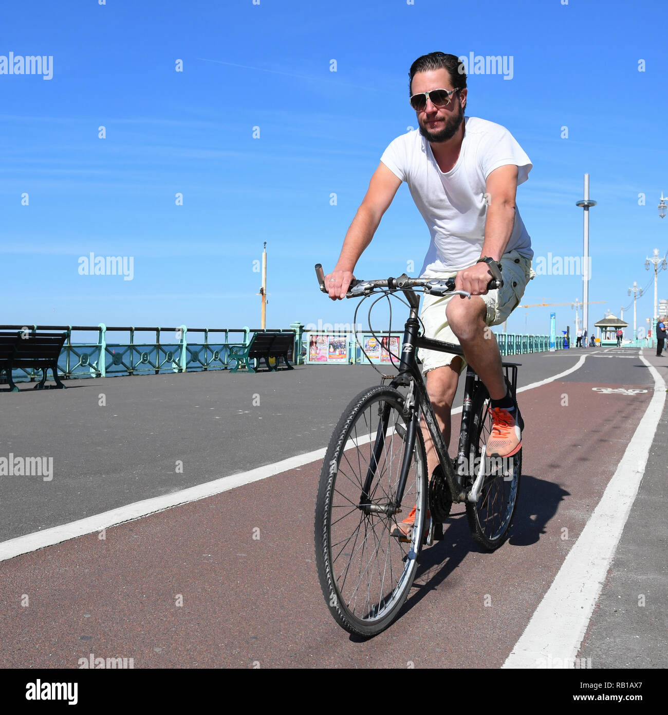 Mann in 20 s oder 30 s Radfahren auf einem Radweg an der Promenade in Brighton, East Sussex, England, UK. Stockfoto