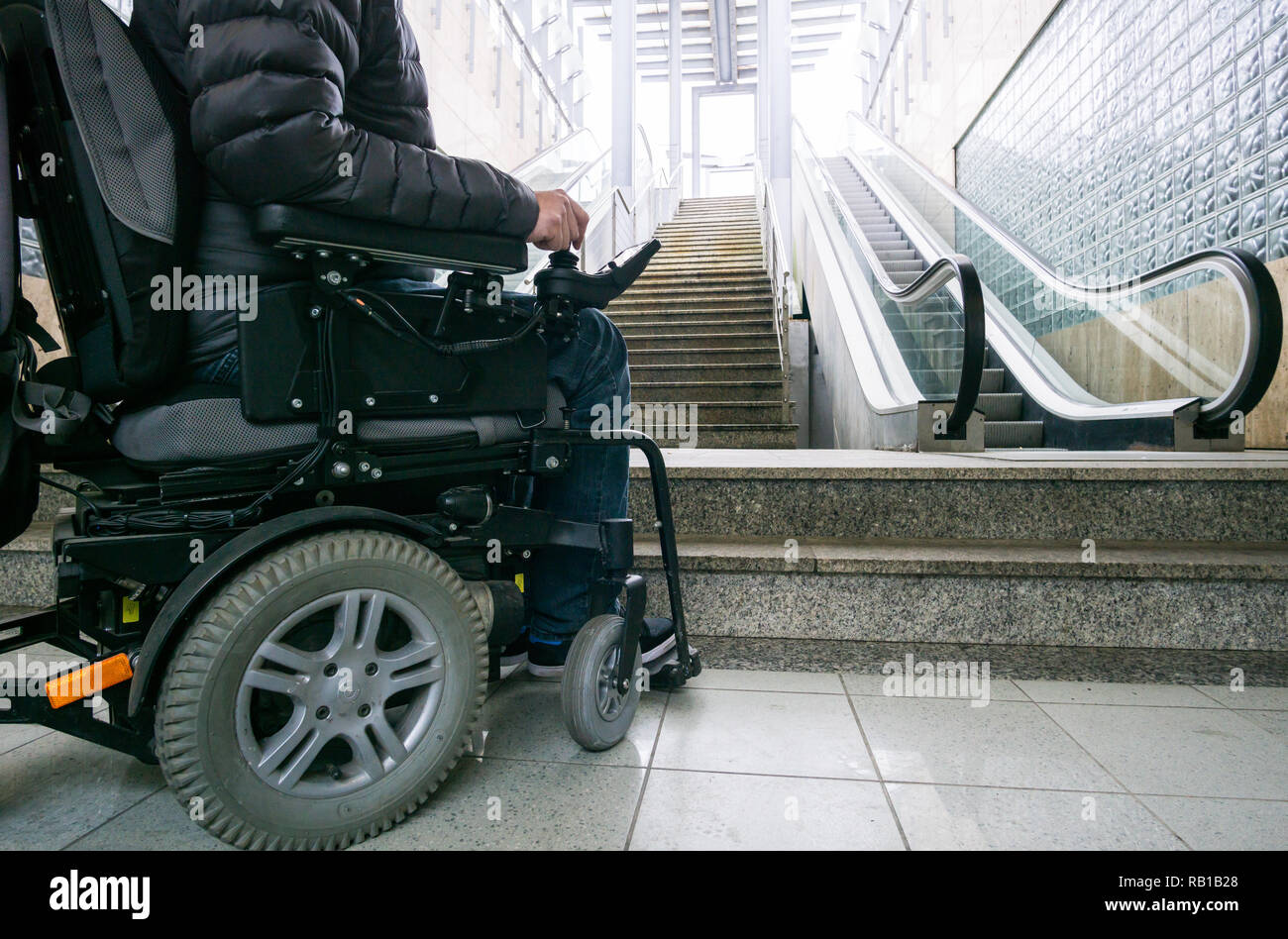 Nahaufnahme des Menschen auf einen Rollstuhl vor rolltreppen und Treppenhaus mit Platz kopieren Stockfoto