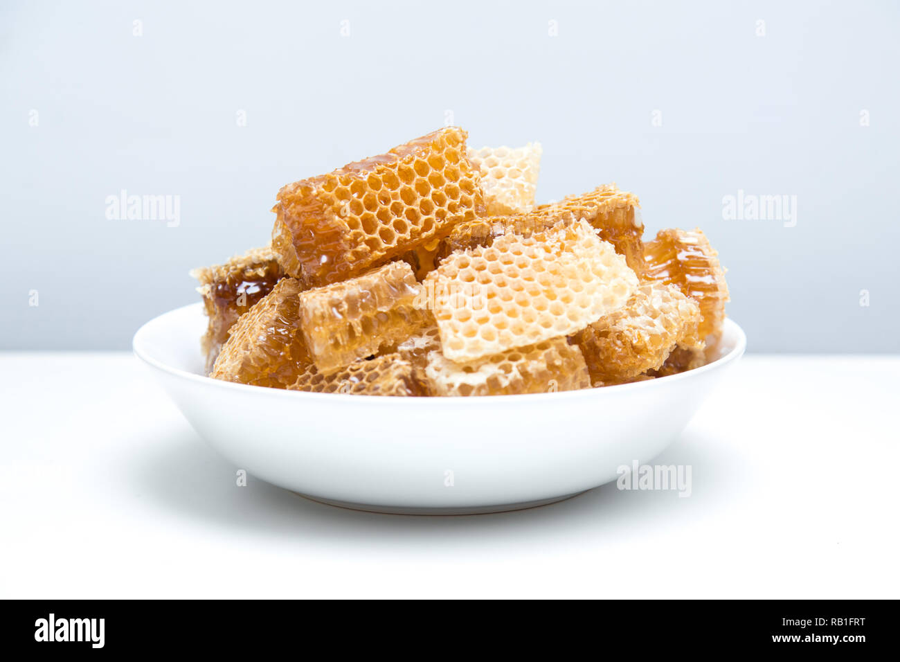 Stücke von Bienenwaben in eine Schüssel geben. Frische Biene Honig in honeycomb Stücke auf weißem Hintergrund. Stockfoto