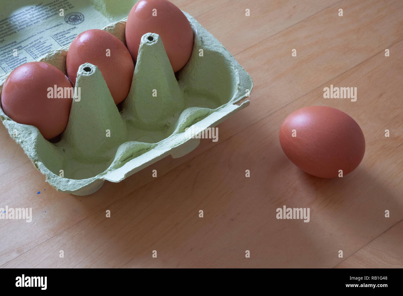 Braune Eier in einem grünen Karton auf hellem Holztisch Stockfoto