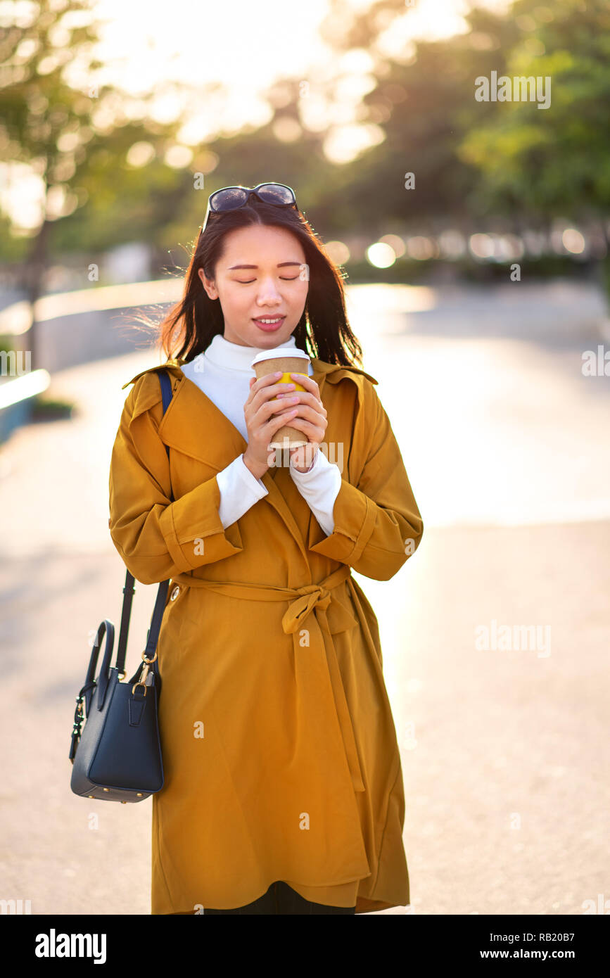 Fröhliches Mädchen mit Tasse Kaffee zu Fuß im Freien Stockfoto