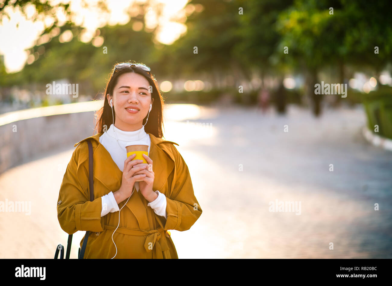 Fröhliches Mädchen mit Tasse Kaffee zu Fuß im Freien Stockfoto