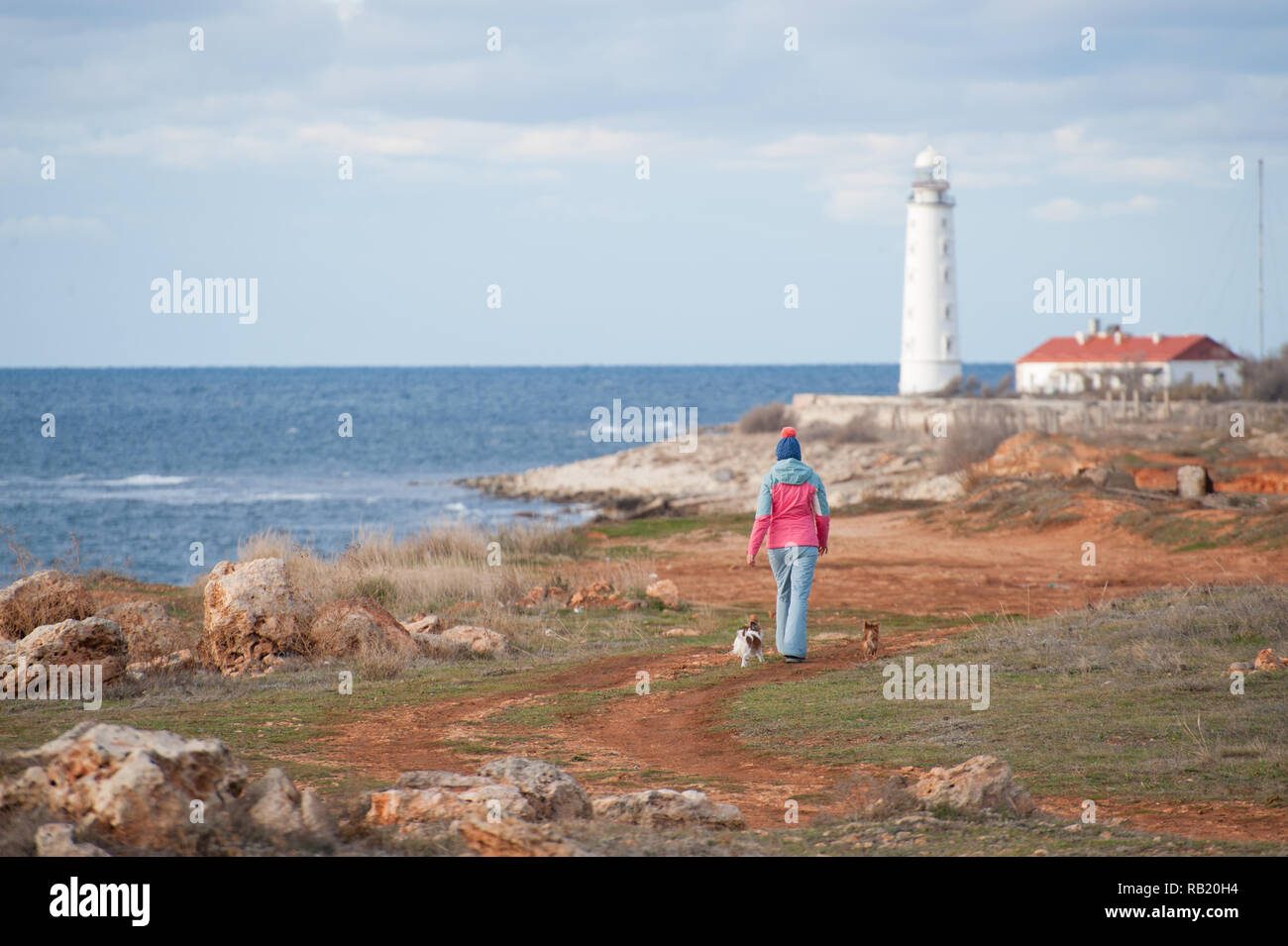 Sport junge Frau mit Feder Trainingsanzug zu Fuß entlang der Küste mit Hunden Stockfoto