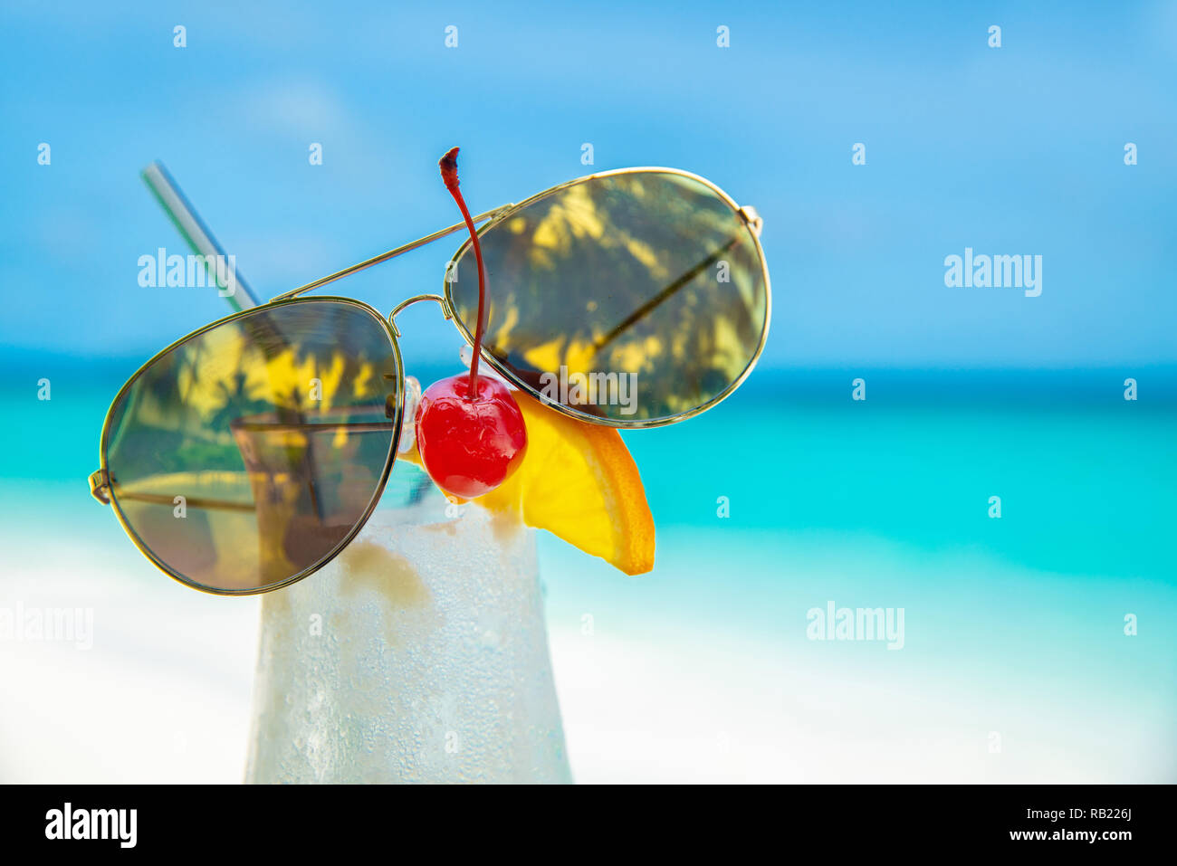 Sonnenbrille auf Cocunut Cocktail und Meer Hintergrund am klaren Himmel Tag Stockfoto