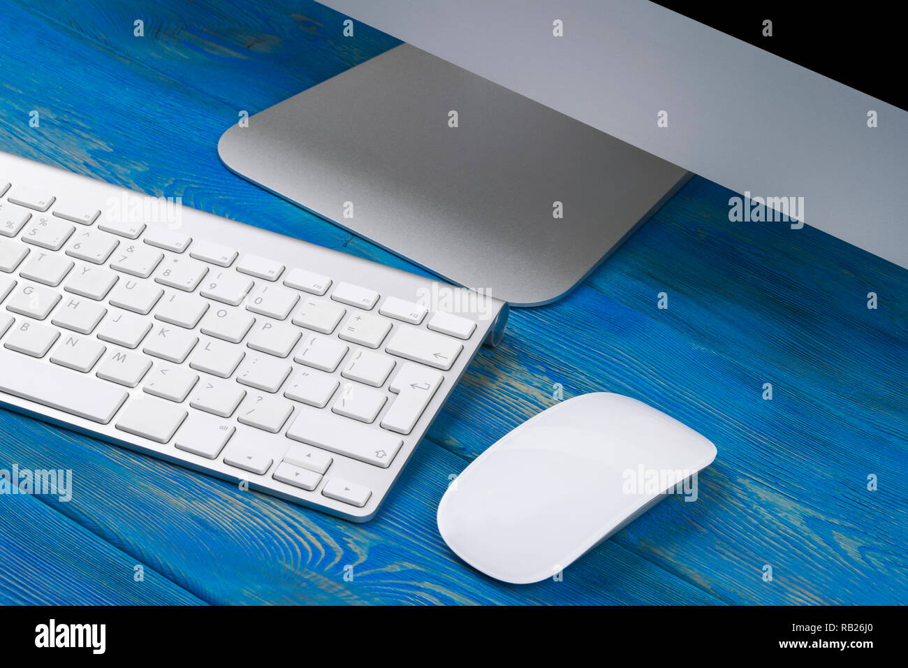 Business Arbeitsplatz mit Computer, drahtlose Tastatur und Maus auf alten blauen Holztisch Hintergrund. Schreibtisch mit Kopie Raum Stockfoto
