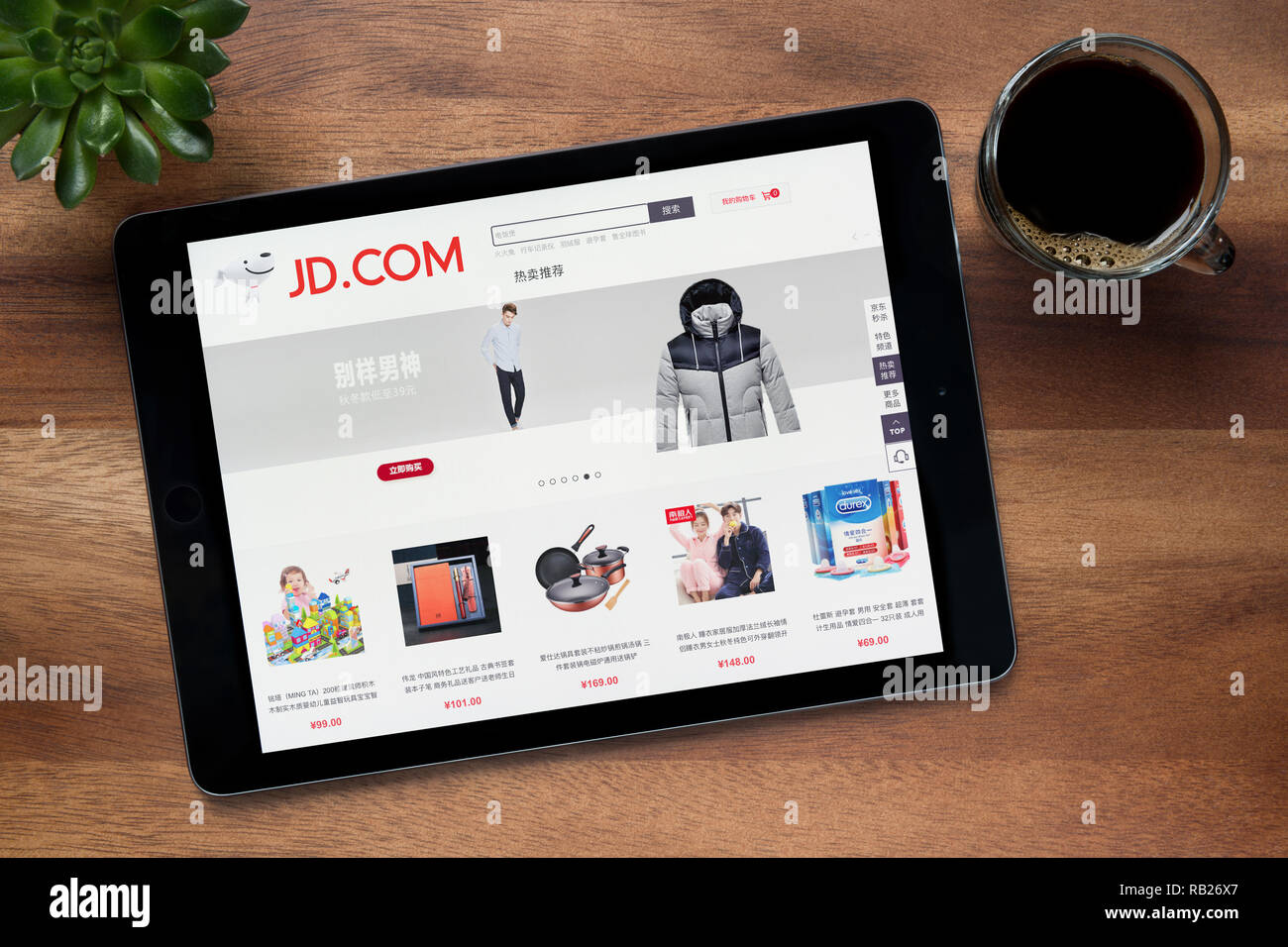 Die Website von JD.com (jingdong) ist auf einem iPad Tablet gesehen, auf einer hölzernen Tisch zusammen mit einem Espresso und einem Haus Anlage (nur redaktionelle Nutzung). Stockfoto