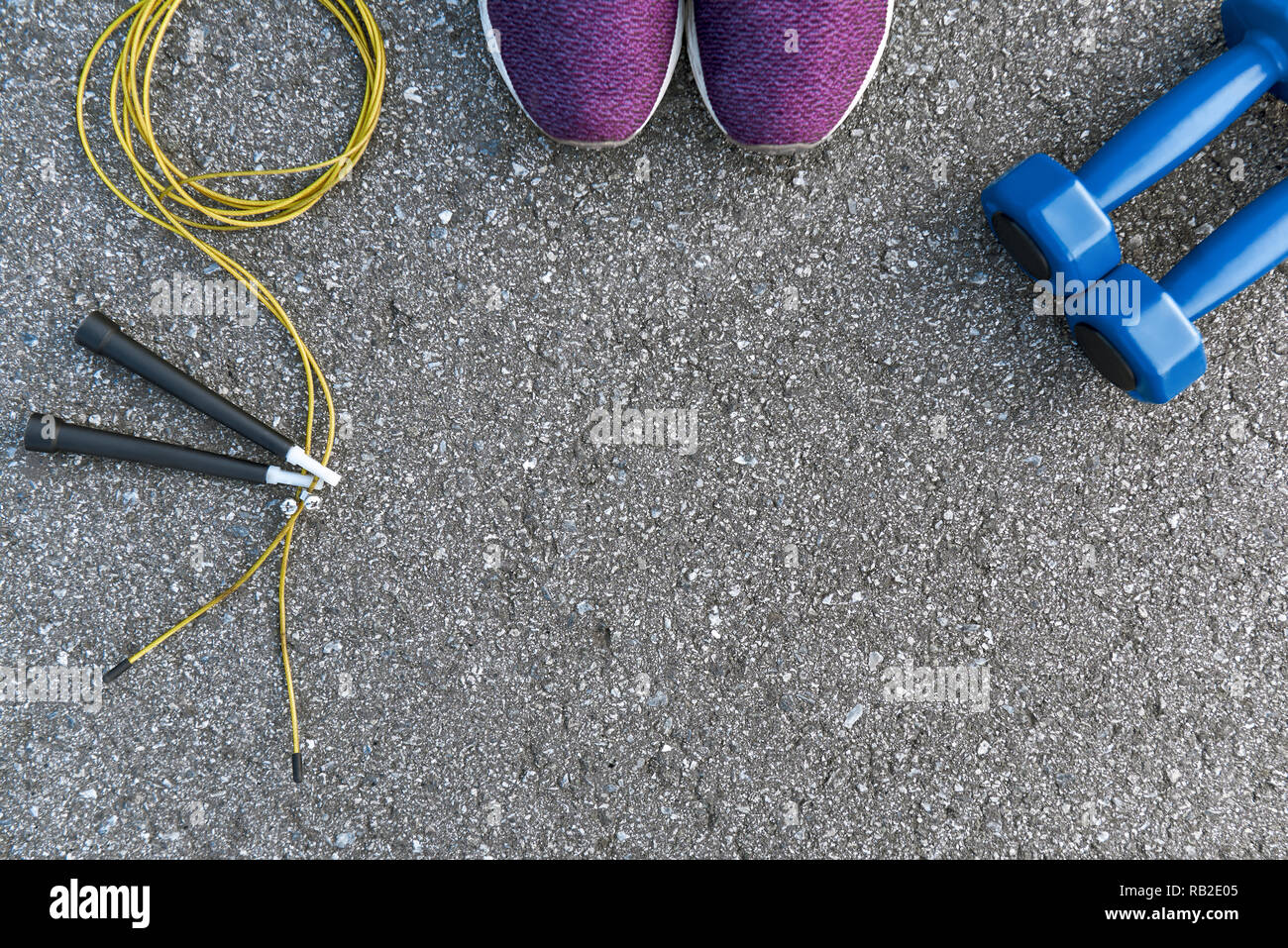Motiviert zum Training. Zwei blaue dumpbells und Seil springen liegen in der Nähe von Purple Sport Schuhe. Fitness als Hobby Stockfoto