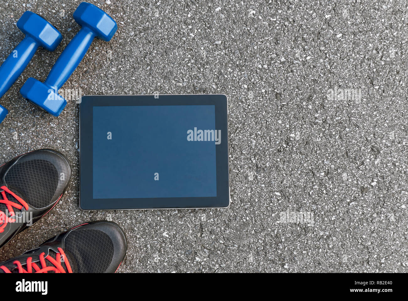 Smart sport Gadgets. Foto von dumpbells, Wasser und schwarze Turnschuhe am Asphalt Hintergrund abgeschnitten. Sport motivation mobile Apps Stockfoto