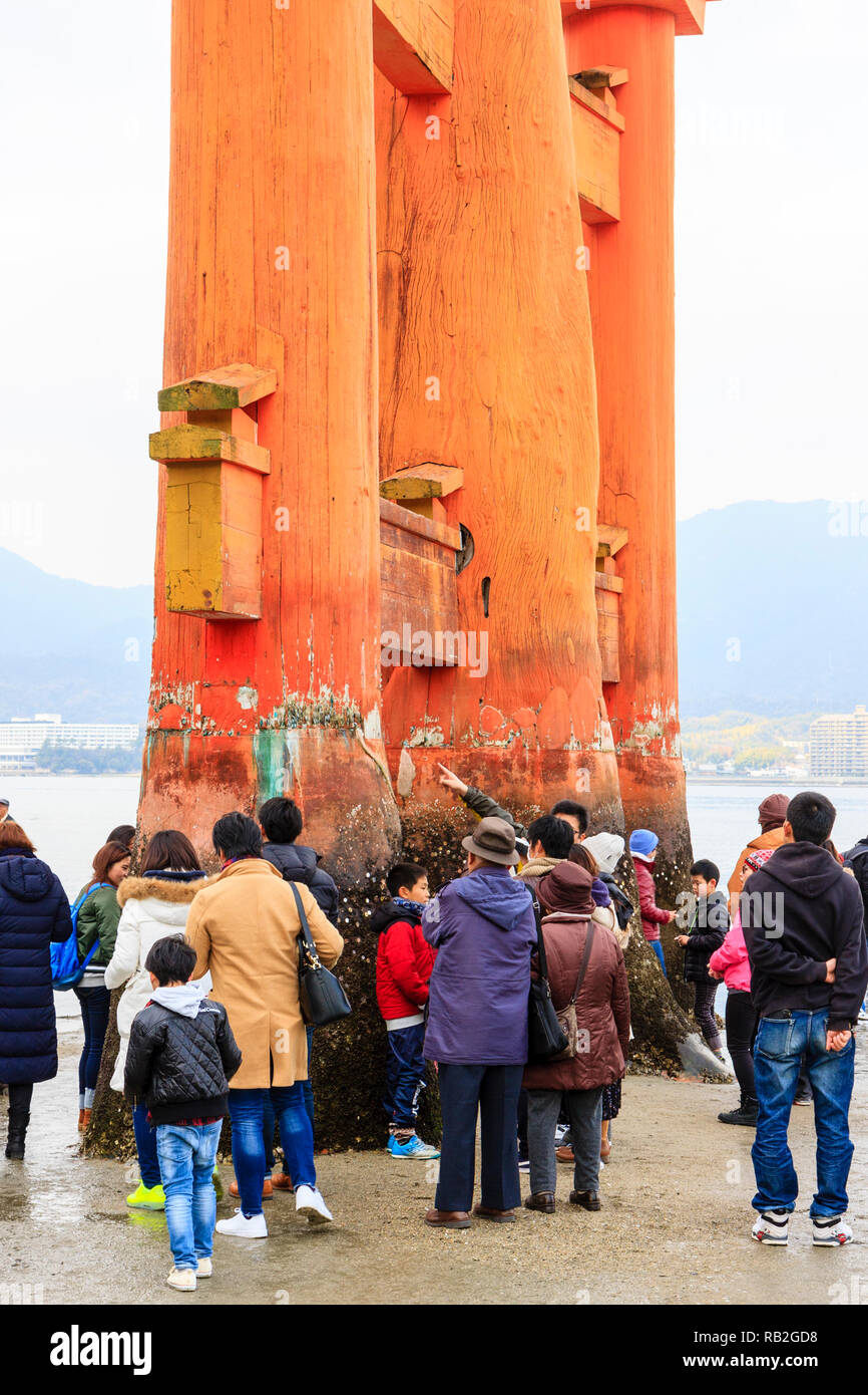 Japan. Die großen Torii an der Itsukushima Shinto Schrein auf der Insel Miyajima bei Ebbe mit Massen von Menschen rund um die drei Säulen an einem Ende. Stockfoto