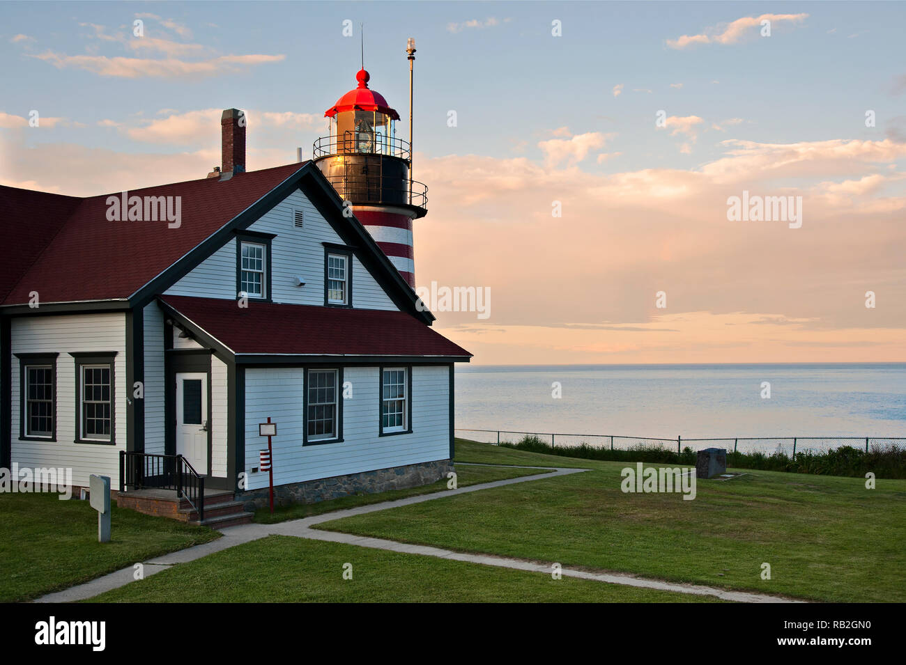 Sonnenuntergang von West Quoddy Head Lighthouse in Maine mit dem markanten roten und weißen Streifen. Sie ist die am nord-östlichen Leuchtfeuer in Amerika. Stockfoto