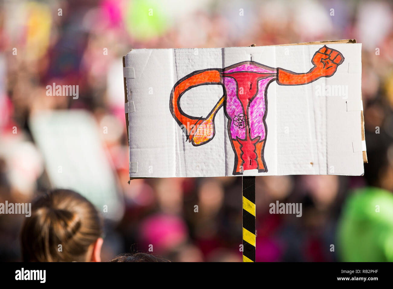 Eine Hand gezeichnet Zeichen, die die reproduktive Organe bilden eine Faust über die Masse während des März 2018 Demonstration der Frauen steigt. Stockfoto